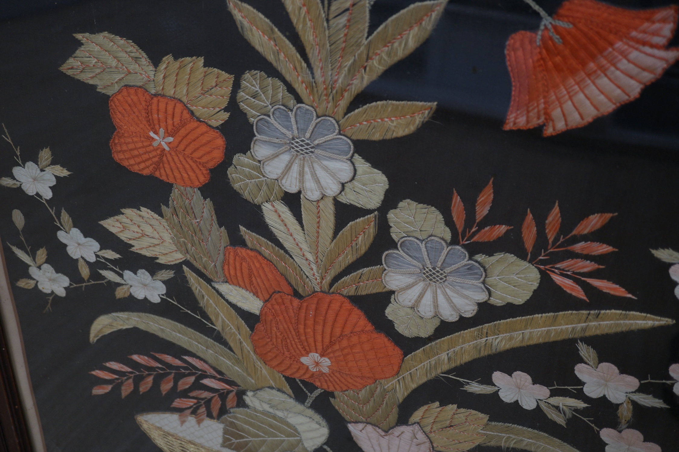 A 1900 to 1920’s Japanese silk embroidery of birds in flight and flowers on a grey background, 131cm high, 52cm wide, together with a Japanese silk and metallic thread still life embroidery on black background, with couc